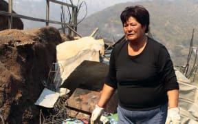 A woman searches through the ruins of her home.