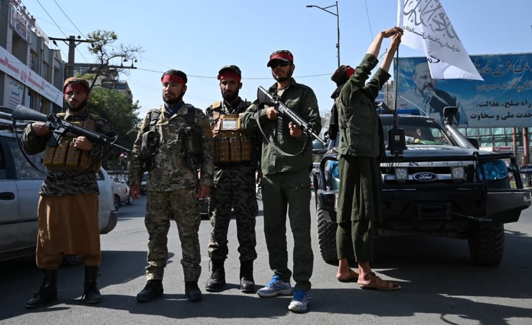 Taliban fighters stand guard along a road in Kabul on September 9, 2021. (Photo by WAKIL KOHSAR / AFP)