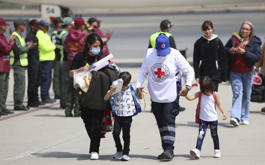 A Venezuelan Red Cross member helps migrant children deported from the US as they arrive at Simon Bolivar International Airport in Maiquetia, Venezuela on February 24, 2025. (Photo by Pedro MATTEY / AFP)