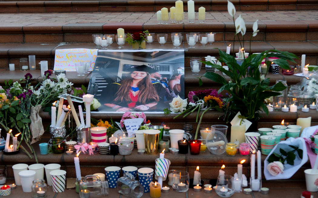 Candles and flowers are laid next to a photo of Grace Millane during the vigil at Civic Square Park in Wellington.