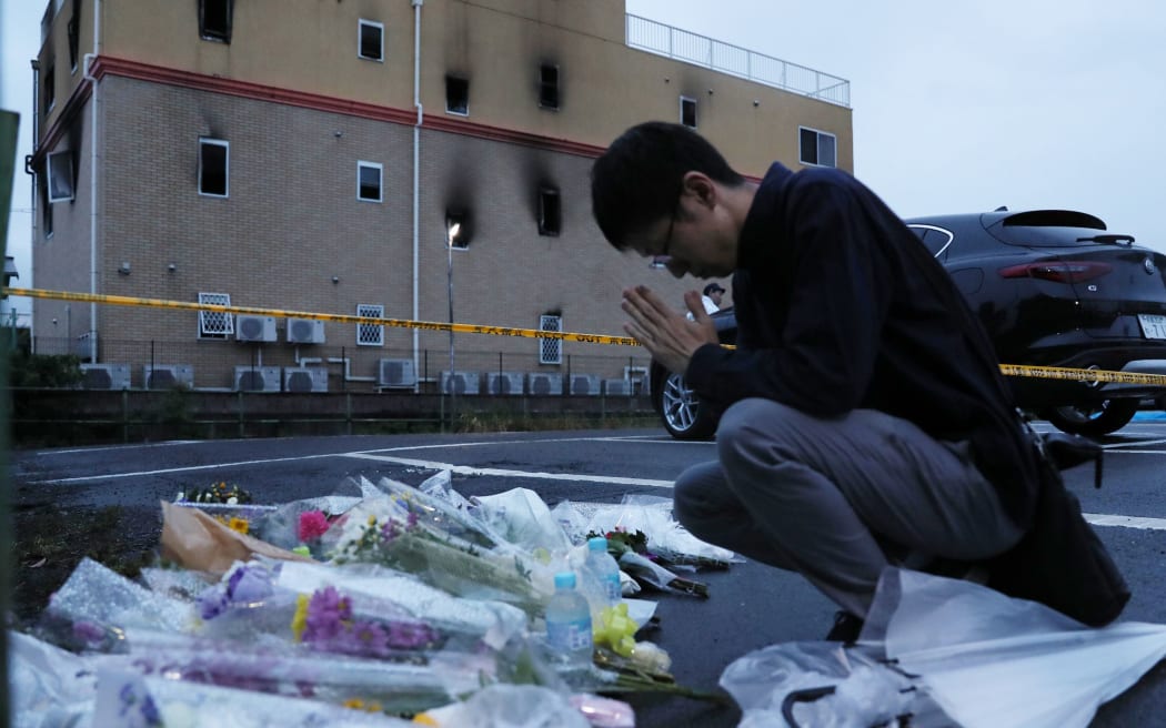 A man places his hands together towards the fire site at Kyoto Animation Co., Ltd. (so-called Kyoani) in Kyoto on July 19, 2019, one day after the arson.
