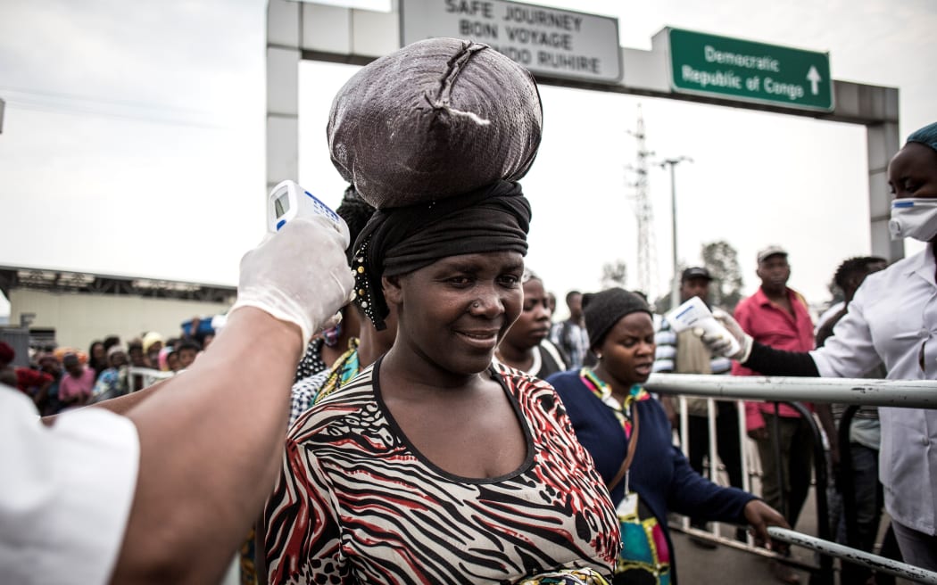 A woman gets her temperature measured at an Ebola screening station as she enters Rwanda from the  Democratic Republic of the Congo, 16 July 2019