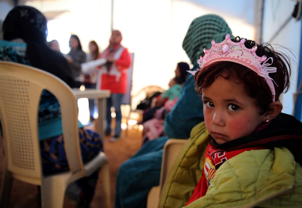 A child sits under a tent with Syrian refugee women attending a class on family planning organised by Doctors Without Borders (MSF) at a makeshift camp by Taybeh village, in Lebanon's eastern Bekaa Valley, on November 15, 2015.