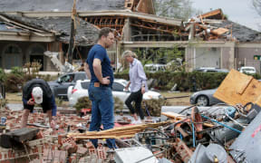LITTLE ROCK, AR - MARCH 31: Kris French (C) and his family search through rubble for a video recorder they think captured a direct tornado strike to their business, Champs Car Wash, after a tornado damaged hundreds of homes and building on March 31, 2023 in Little Rock, Arkansas. Tornados damaged hundreds of homes and buildings Friday afternoon across a large part of Central Arkansas. Governor Sarah Huckabee Sanders declared a state of emergency after the catastrophic storms that hit on Friday afternoon. According to local reports, the storms killed at least three people.   Benjamin Krain/Getty Images/AFP (Photo by Benjamin Krain / GETTY IMAGES NORTH AMERICA / Getty Images via AFP)