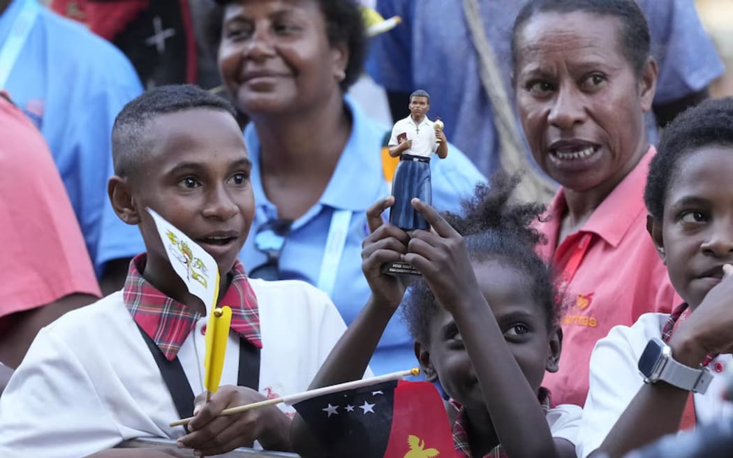 A child holds up a statue of Peter ToRot, who was beatified by Pope John Paul II.  (AP: Mark Baker)