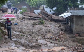 People walk between washed away structures in Blantyre on March 14, 2023, caused by heavy rains following cyclone Freddy's landfall. - Cyclone Freddy, packing powerful winds and torrential rain, killed more than 100 people in Malawi and Mozambique on its return to southern Africa's mainland, authorities said on March 13, 2023.