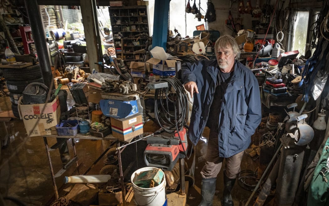 Bryce Allan who has not been able to work since March, stands in his flooded garage.
