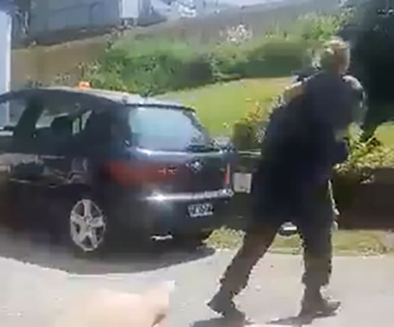 Still from video showing an armed offender squad policeman rescuing a girl from a house in Tauranga 24 November 2019 after a man had been shot by police during a hostage situation at the address