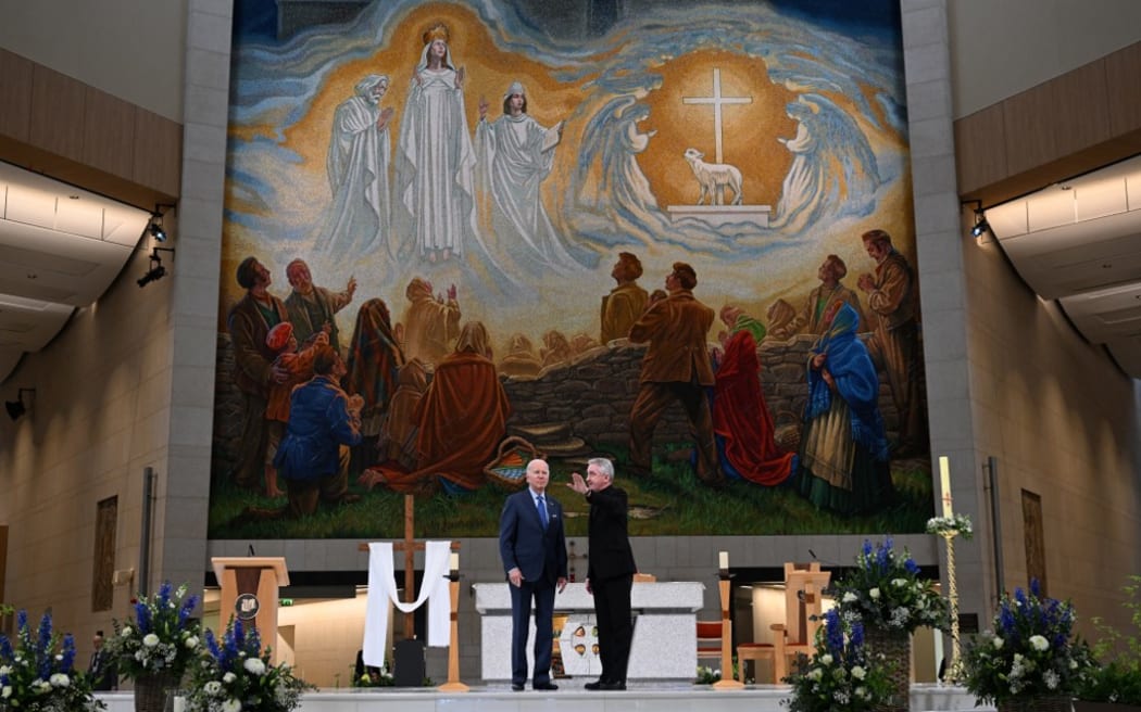 US President Joe Biden (L) speaks with Father Richard Gibbons (R) in front of the mosaic as he visits Knock Shrine, on April 14, 2023, on the last day of a four day trip to Northern Ireland and Ireland.