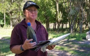 Sheena Martin holds a bottle of the dirty, silty water from the Waihi Dam.