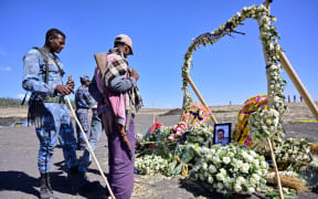 An ethiopian federal policeman and an Oromo tribesman look at a memorial to victims at the crash site of an Ethiopian airways operated Boeing 737 MAX aircraft on March 16, 2019  in Oromia region. -