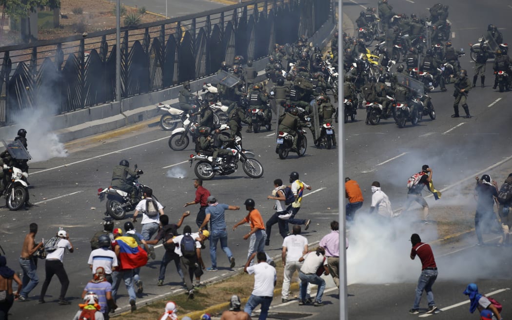 Opponents to Venezuela's President Nicolas Maduro confront loyalist Bolivarian National Guard troops firing tear gas at them, outside La Carlota military airbase in Caracas, Venezuela, Tuesday, April 30, 2019.