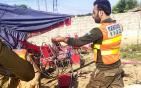 This handout photograph released by Pakistan's Emergency Rescue 1122 Service on 30 July  2023 shows rescue workers at the site of a bomb blast in Bajaur district, in Pakistan's Khyber Pakhtunkhwa province.