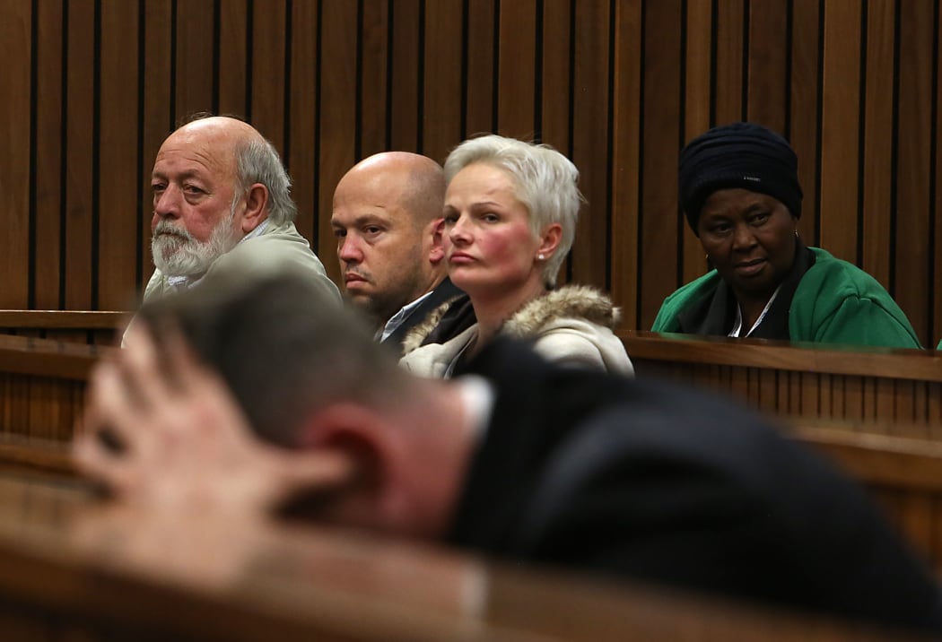 South African Paralympian Oscar Pistorius (Foreground) holds his head in his hands as members of Reeva Steenkamp's family including her father Barry Steenkamp(L), looks on during his resentencing hearing.