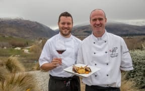 Mark Southon and Werner Hecht-Wendt with dish and wine in front of Mount Difficulty