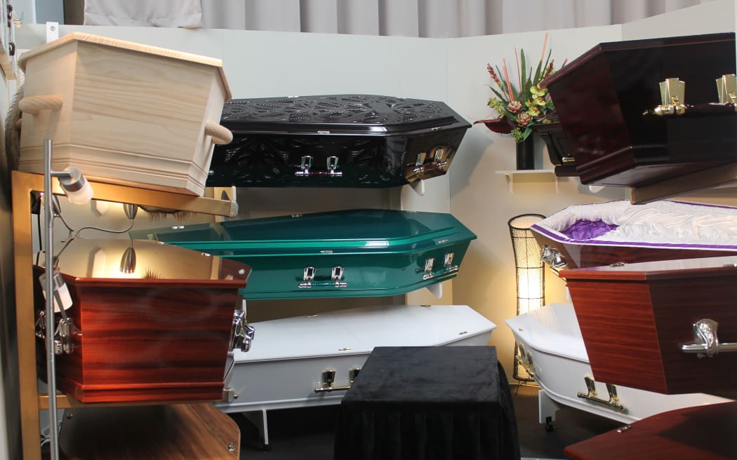 Coffins on stands on shelves ranging from adark carverd version to bright aqua