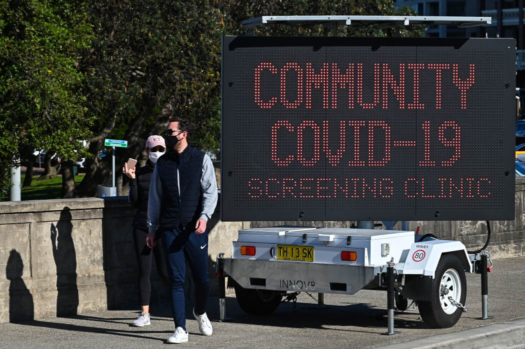 People walk past a sign for a Covid-19 testing clinic at Bondi Beach in Sydney 27 June, 2021.