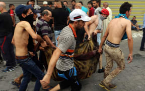 Iraqis evacuate a body from the site of a suicide car bombing claimed by the Islamic State group on July 3, 2016 in Baghdad's central Karrada district.