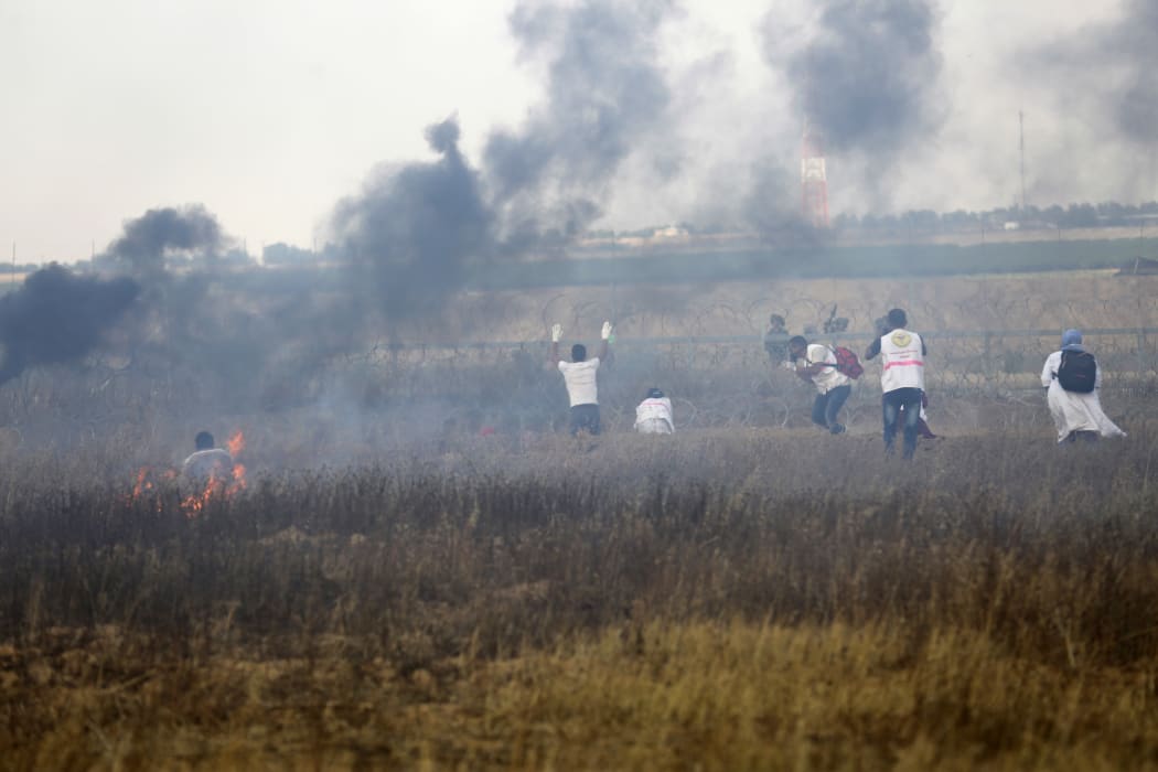 Palestinian paramedics approach the barbed wire fence with Israel to tend to injured protesters during clashes along the border east of Khan Yunis in the southern Gaza strip on June 1, 2018.