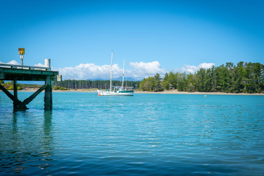 Wharf at Mapua with slopp moored in channel of Waimea Estuary on Tasman Bay in South Island New Zealand.