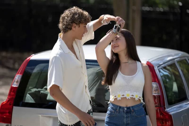 A teenage boy and girl look at each other fondly.