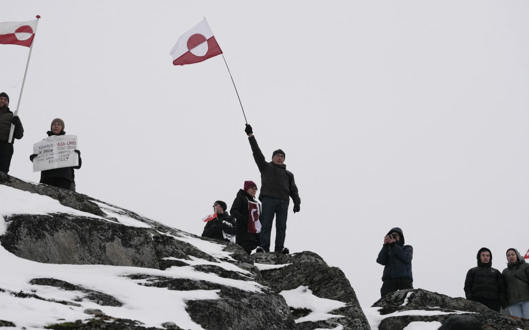 People wave Greenlandic flags as they take part in a demonstration that gathered almost a third of the city population to protest against the US President's plans to take Greenland, on January 17, 2026 in Nuuk, Greenland. US President Donald Trump escalated his quest to acquire Greenland, threatening multiple European nations with tariffs of up to 25 percent until his purchase of the Danish territory is achieved. Trump's threats came as thousands of people protested in the capital of Greenland against his wish to acquire the mineral-rich island at the gateway to the Arctic. (Photo by Alessandro RAMPAZZO / AFP)