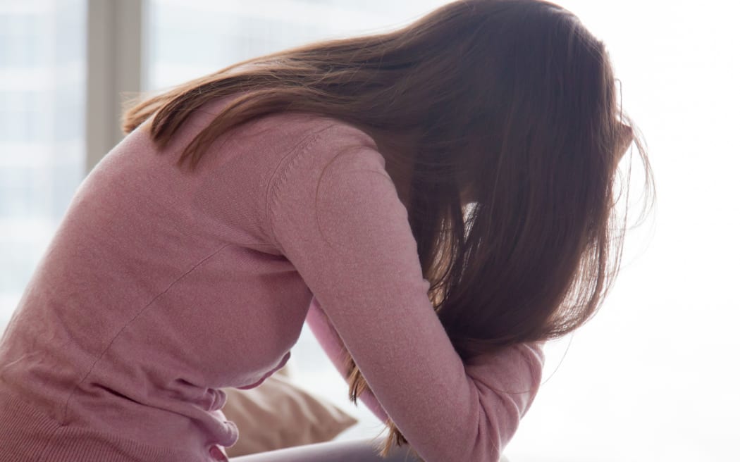 Young depressed woman sitting alone holding her head in hands, sad girl, problems at work, troubles in relationships,