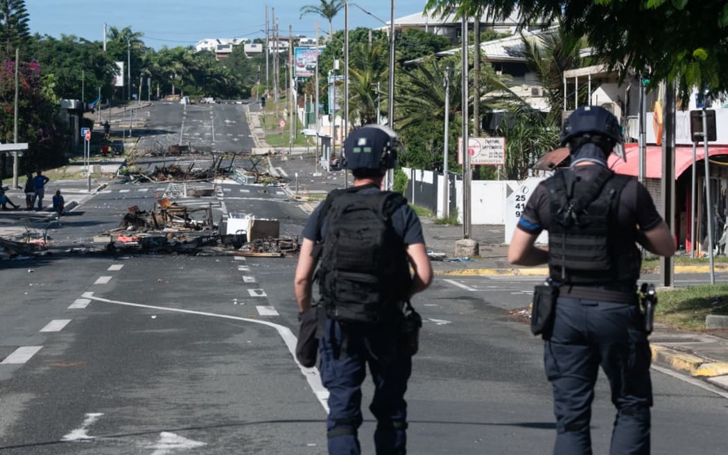 Police patrol a street blocked by debris and burnt out items following overnight unrest in the Magenta district of Noumea, France's Pacific territory of New Caledonia, on May 18, 2024. Hundreds of French security personnel tried to restore order in the Pacific island territory of New Caledonia on May 18, after a fifth night of riots, looting and unrest. (Photo by Delphine Mayeur / AFP)