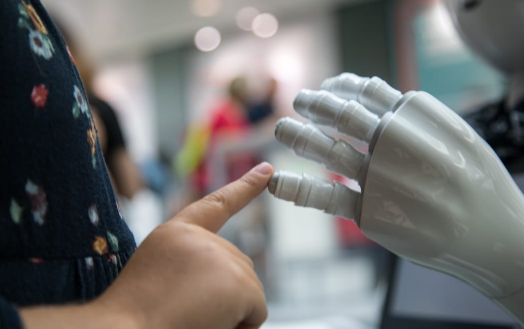 Child's finger touches the hand of a robot