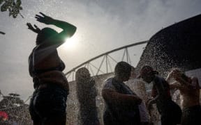 Fans of US singer Taylor Swift cool off as they queue outside the Nilton Santos Olympic Stadium before Swift's concert, "Taylor Swift: The Eras Tour", amid a heat wave in Rio de Janeiro on November 18, 2023. American superstar Taylor Swift on Saturday was mourning the death of a 23-year-old fan during her first show in Brazil before a crowd of 60,000. The death occurred as much of central and southeastern Brazil has been suffering an unusually oppressive springtime heat wave. (Photo by Tercio TEIXEIRA / AFP)