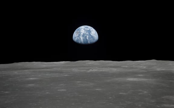 This July 1969 NASA file photo obtained July 16, 2019 shows a file view of Earth rising over the Moon's horizon taken from the Apollo 11 spacecraft. - The lunar terrain pictured is in the area of Smyth's Sea on the nearside.