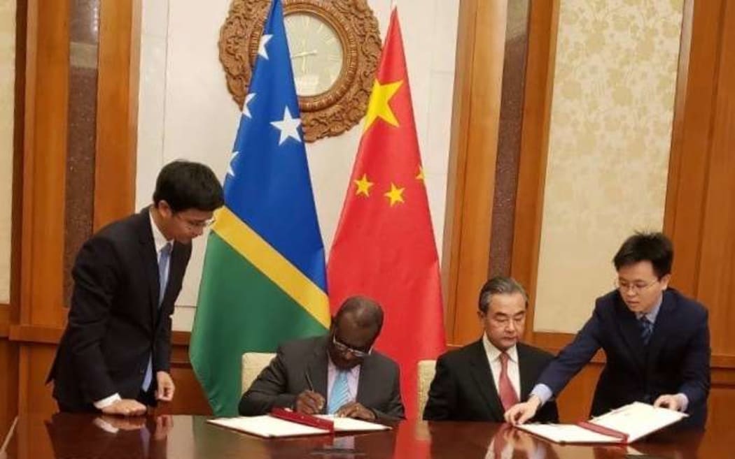 Jeremiah Manele and Wang Yi signing the communique.