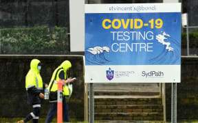 Medical officers walk past a sign board of Covid-19 testing center on Bondi Beach in Sydney on May 6, 2021.