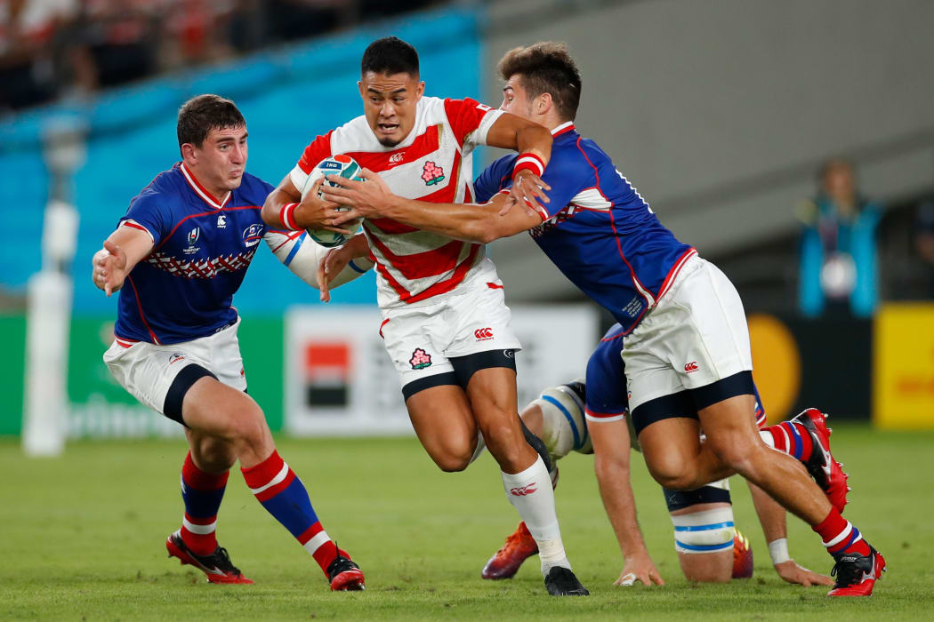 Japan's fly-half Yu Tamura (C) is tackled during the Japan 2019 Rugby World Cup Pool A match against Russia.