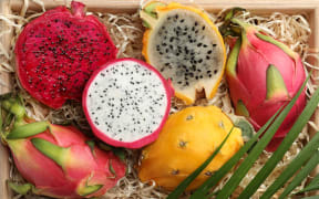 Cut and whole dragon fruits in crate, top view