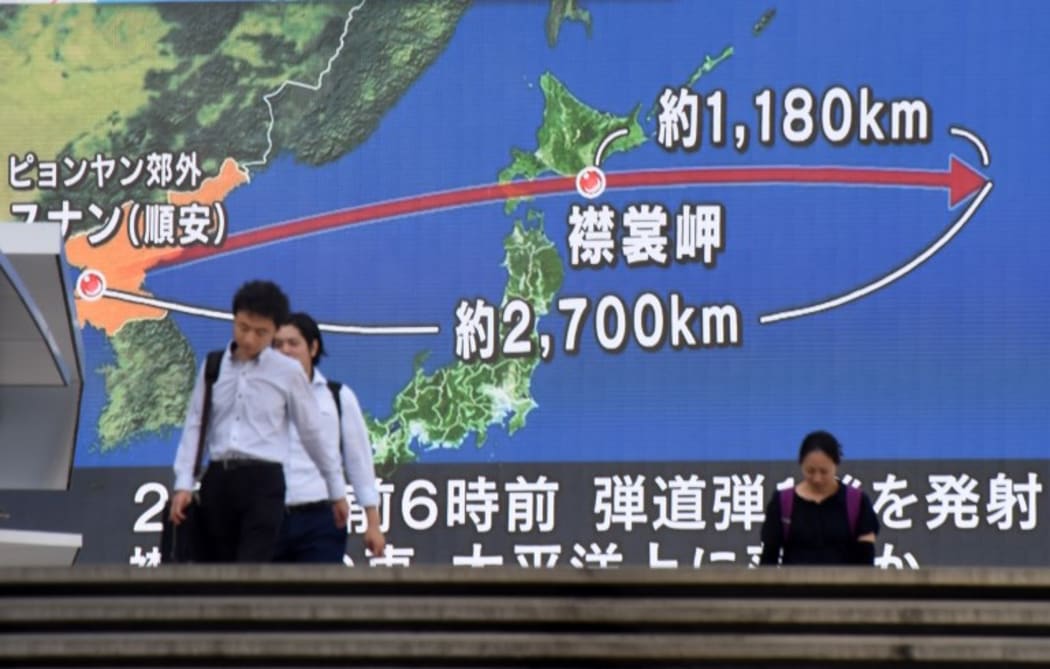 In August 2017, pedestrians in Tokyo walk in front of a screen displaying the trajectory of North Korean missiles over Japan.