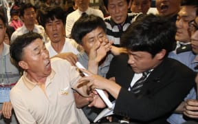 Family members of victims struggle with a security officer, right, on Tuesday.