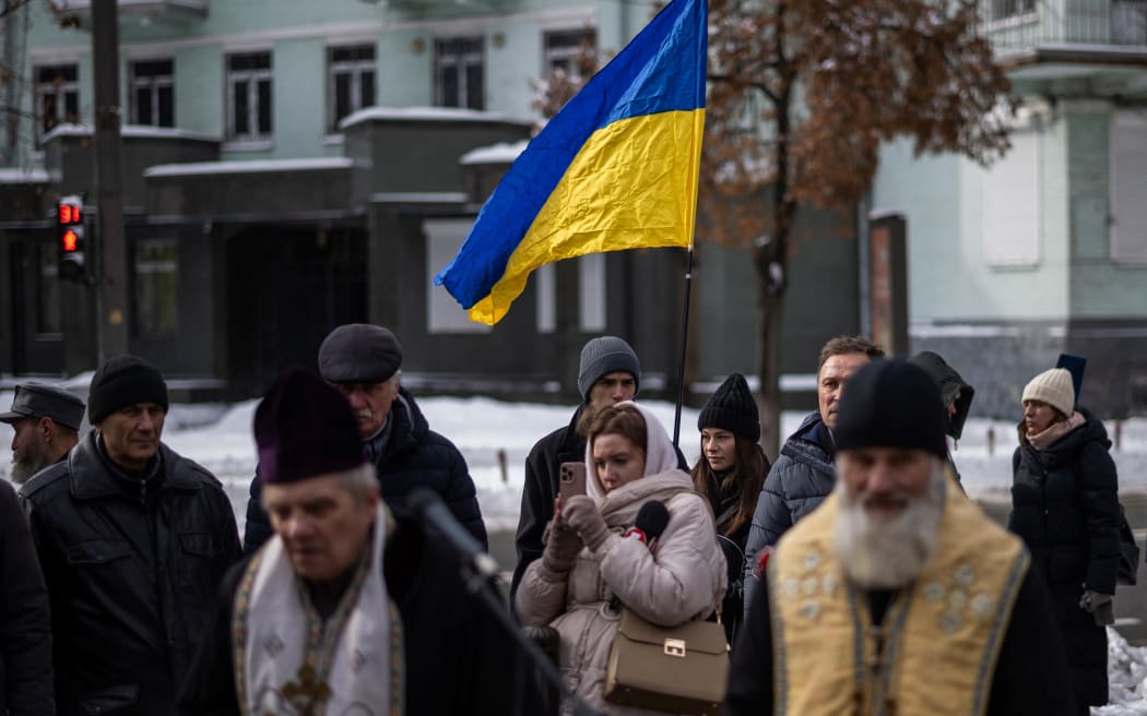 People attend a memorial service honouring the victims of the peaceful march to the Ukrainian Verkhovna Rada on February 18, 2014, during the mass Euromaidan protests, in Kyiv on February 18, 2026, amid the Russian invasion of Ukraine. (Photo by HENRY NICHOLLS / AFP)