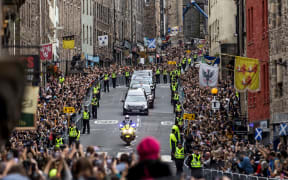Members of the public gather along the Royal Mile to watch the hearse carrying the coffin of Queen Elizabeth II, as it is driven through Edinburgh towards the Palace of Holyroodhouse, on September 11, 2022.