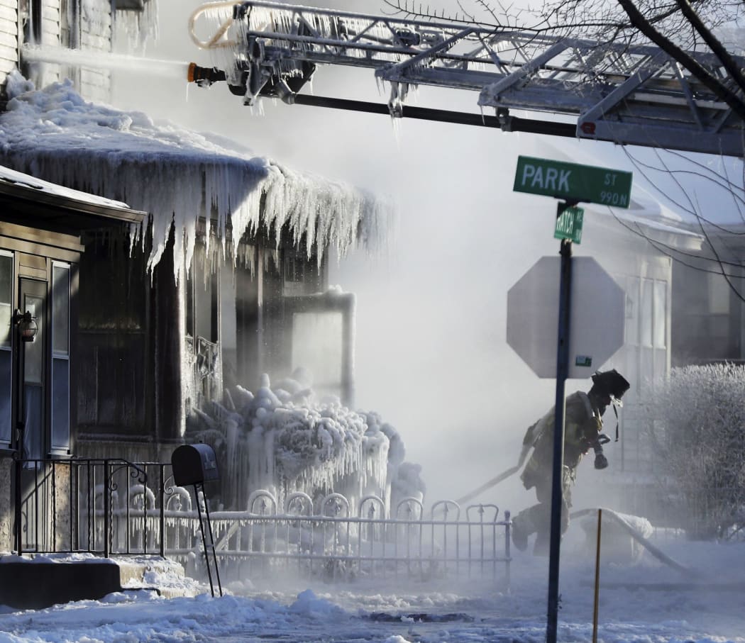 Firefighters at the scene of a house fire in Saint Paul, Minnesota during a arctic deep freeze on 30 January.