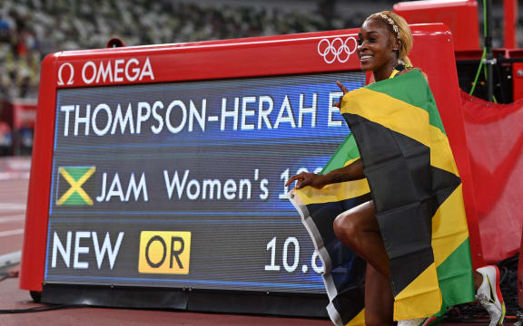 Jamaica's Elaine Thompson-Herah poses with the scoreboard as she celebrates after winning the women's 100m final during the Tokyo 2020 Olympic Games at the Olympic Stadium in Tokyo on July 31, 2021.
