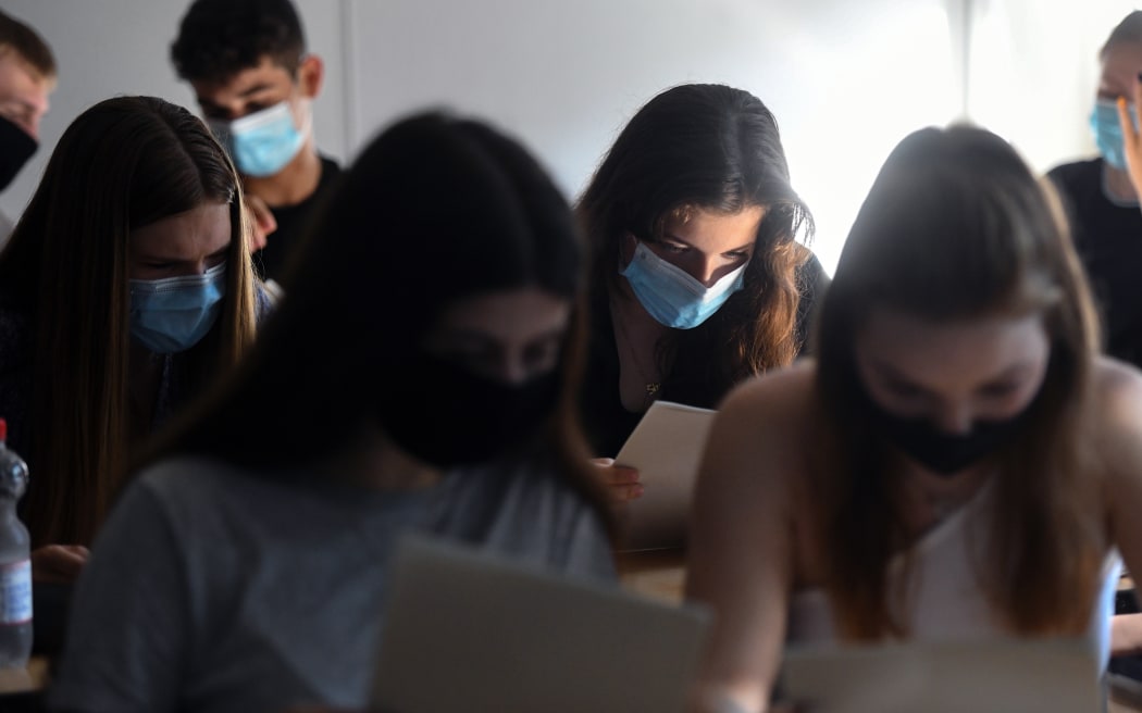 Students of the eleventh grade sit with face masks in a classroom of the Phoenix high school in Dortmund, western Germany, on 12 August 2020, amid the novel coronavirus COVID-19 pandemic.