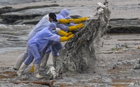 Sri Lankan Navy soldiers work to remove debris washed ashore from the burning X-Press Pearl on a beach in Colombo on 28 May, 2021.