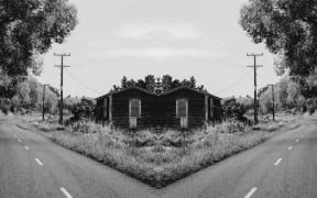 A gothic, black-and-white mirror image of a street in Whanganui featuring a ram-shackle house and powerlines.