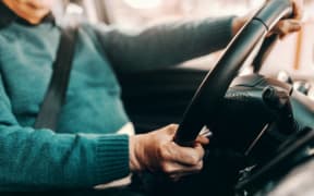 Close up of Caucasian senior man driving his car. Both hands on steering wheel.