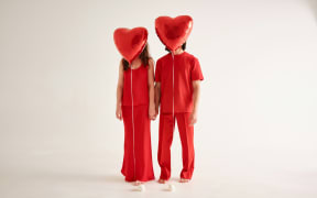 Generic pic for Valentine's Day showing two people dressed in red with red heart-shaped balloons covering their faces
