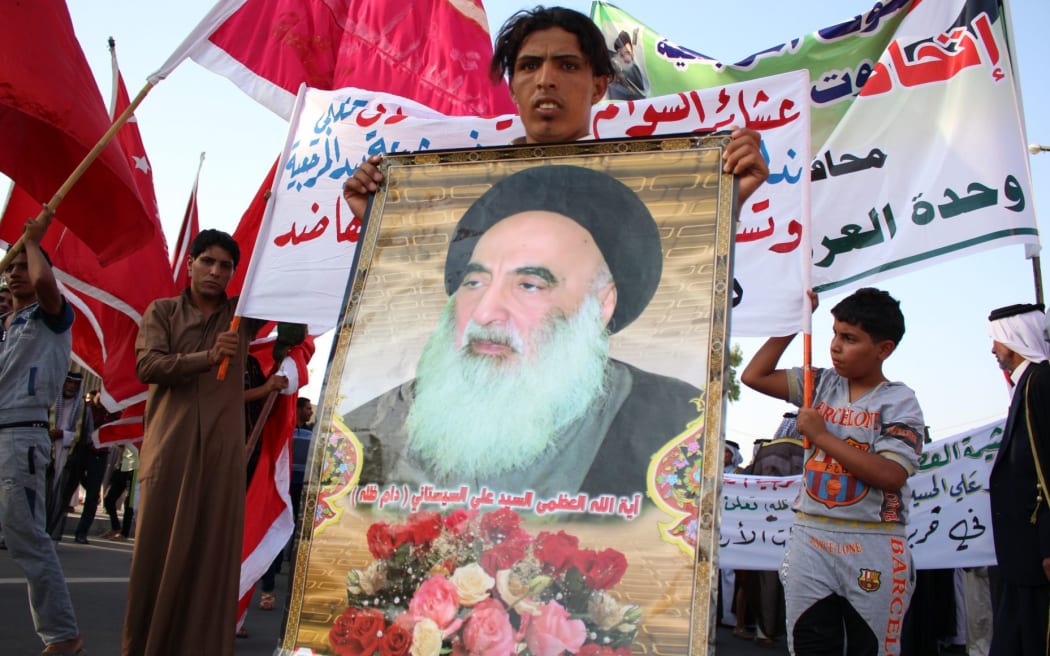 An Iraqi man holds a placard bearing a portrait of Ayatollah al-Sistani.