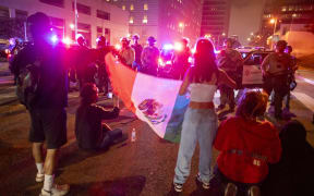 Protesters with a Mexican flag face off with Sheriff deputies during a protest following federal immigration operations in Los Angeles, California, on 8 June, 2025.