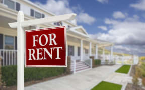 For rent sign in front of two-storey houses.