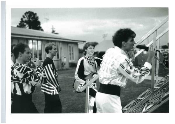 Four men in elaborate costumes play music in front of a building.